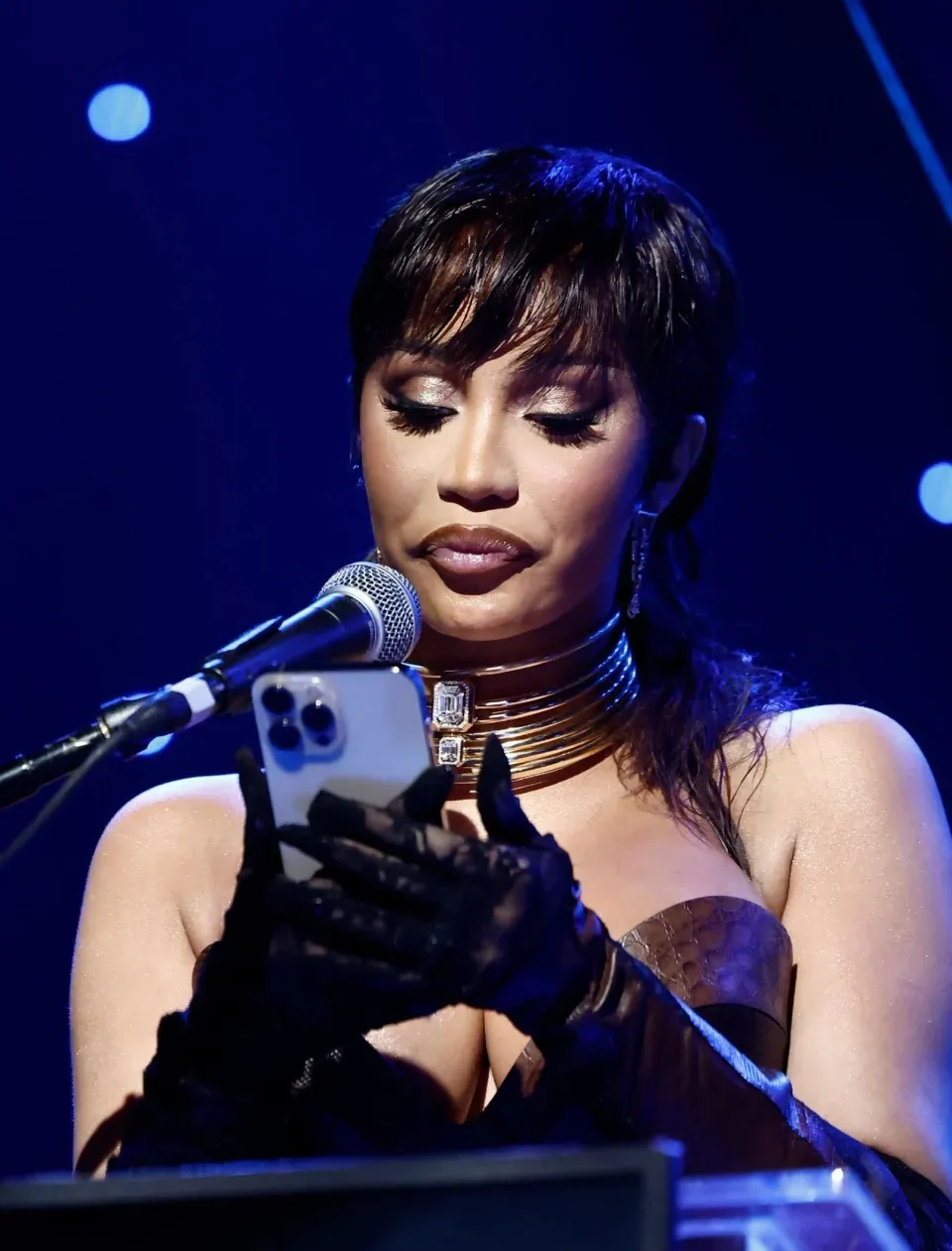 Cardi B onstage with her phone in her hands