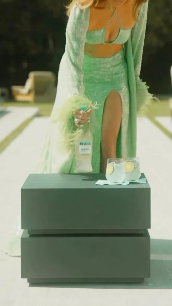 Jennifer Lopez wears green sequin and feather look in Delola Light Margarita ad.